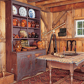Redware and Delft line the shelves of a red step-back cupboard in the barn. A brass telescope and spyglass are a nod to the maritime history of the area.