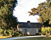 Fig. 15: HCF's easement protects the acreage and outbuildings around the main residence at Mulberry Plantation, including this restored slave cabin. The cabin, of wood-frame construction, would have housed two families. The pond behind the cabin is a former impoundment used for rice cultivation. Photography by Rick McKee.