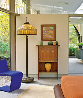 The Tiffany floor lamp, with its curtain glass border and pigtail finial, glows at night and echoes the yellow-green hostas in the garden in the daytime. The Gustav Stickley desk designed by the architect Harvey Ellis provides a place for a select collection of sculptural Grueby pottery with its leathery glaze. The painting is by plein air artist Henry Ryan MacGinnis (1875–1962). The contemporary purple Phillips chair by Rodolfi Dordoni for Minotti was made in Italy. The adjoining bathroom, with its pod-shaped shower, which Dennis designed with his uncle, sculptor Harold Kimmelman, has views of the secluded garden. For privacy, there are pocket doors, electrically operated shades, and a glass panel from the top of the wall to the ceiling.