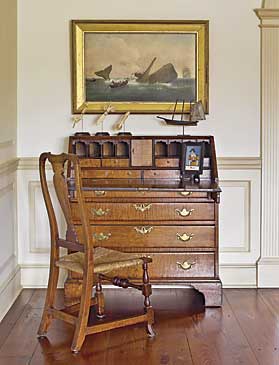 The figured maple Chippendale slant-front desk was one of the couple’s early purchases. The German églomisé painted scene is a rendering of Autumn, circa 1830. A Spanish-foot Queen Anne maple side chair is pulled up to the desk. The couple purchased the painting of the whaling scene from Fred Giampietro at the Winter Antiques Show in 1988. This picture reminds the couple of Nantucket, where they have a home, and ties in with the island’s history of whaling. The miniature ship weathervane, from Olde Hope, was possibly used on an out building such as a shed. Continuing the nautical theme are three scrimshaw pie crimpers, purchased from Hyland Granby Antiques.